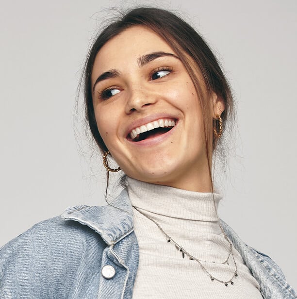 Mujer sonriendo con una sonrisa brillante y dientes blancos. Enjuague bucal Colgate Total Clean Mint.