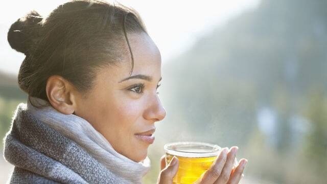 person standing outdoors and drinking tea