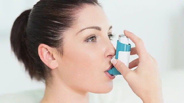 woman using inhaler to aid breathing
