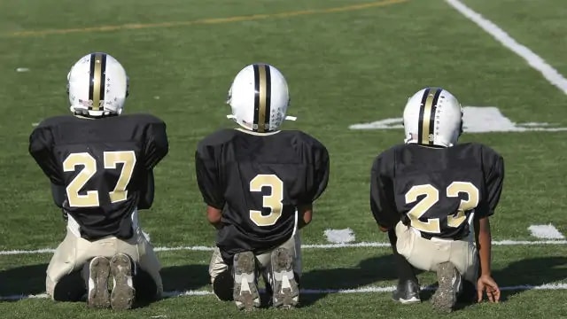 three young American football players are ready to play in the field
