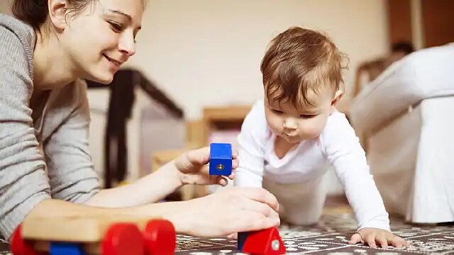 A woman and an infant playing with blocks
