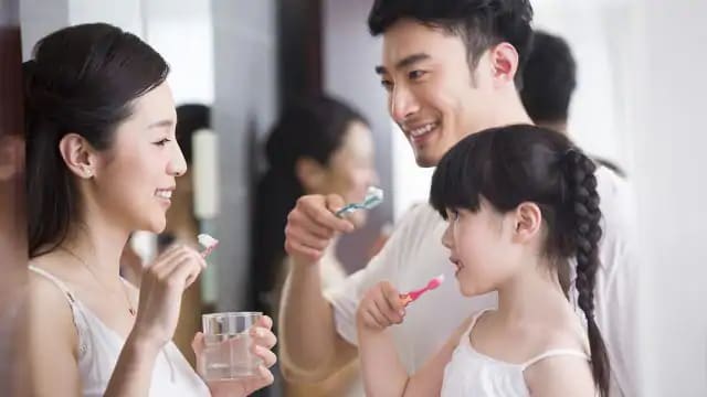 a family is brushing teeth together at home