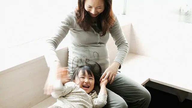 pregnant woman playing with daughter