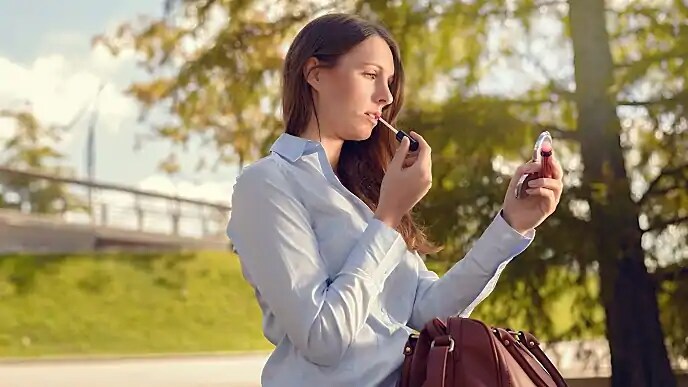 woman putting on lip gloss