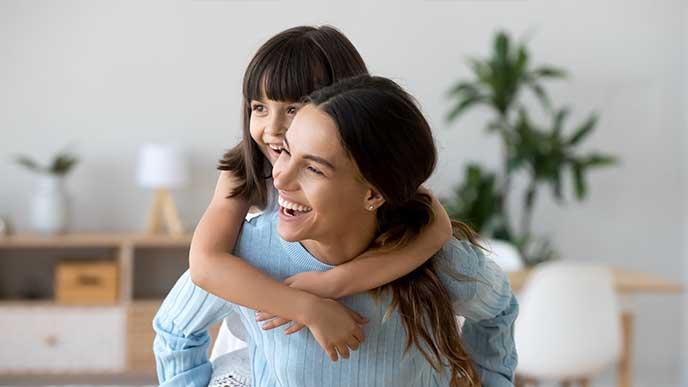 Cheerful mother and daughter playing in the living room