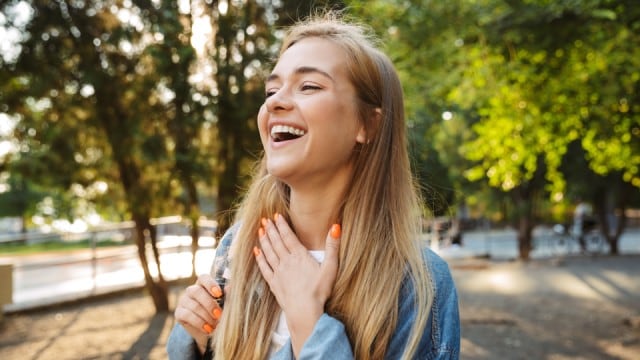 Cheerful young woman walking outside in nature green park.