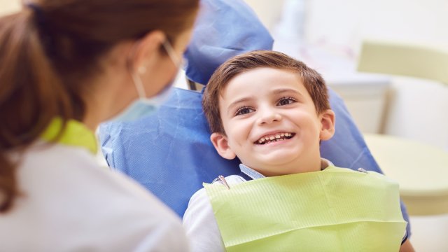 a smiling young boy is ready for his dental treatment and the dentist sits next to him