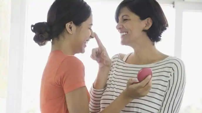 mother is putting make up on her daughter's face