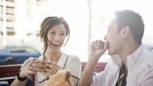 a man and a woman are laughing and eating together outdoors a man and a woman are laughing and eating together outdoors