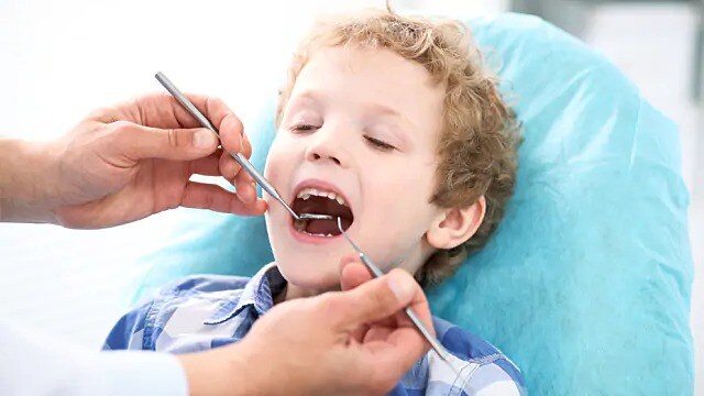 dentist performing tooth exam on child