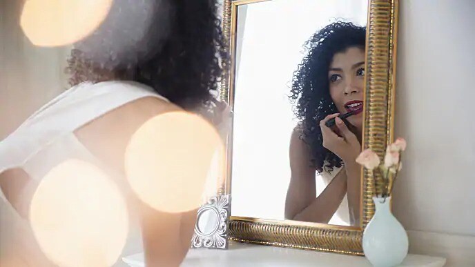 woman putting on lipstick