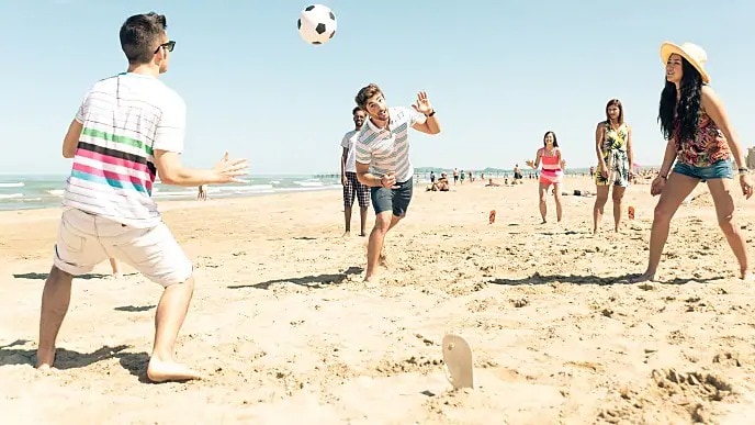 people playing soccer on the beach