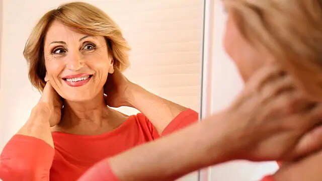 older woman smiling in the mirror