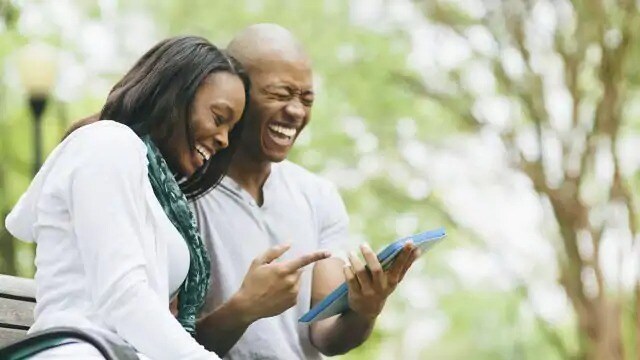 A couple is laughing while they are looking at the tablet
