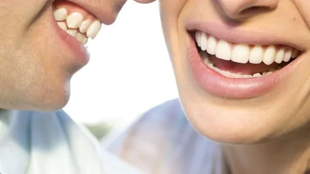 a close up of two adults are smiling together with fresh breath and bright teeth
