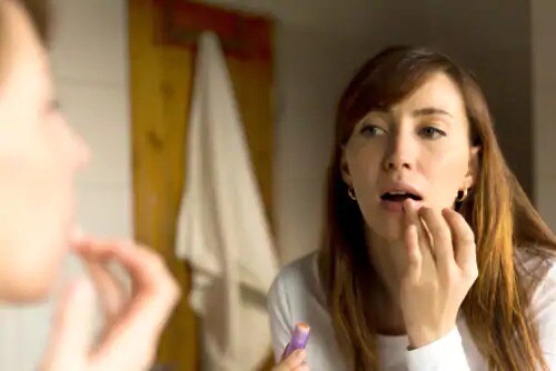 woman putting ointment on lip scab