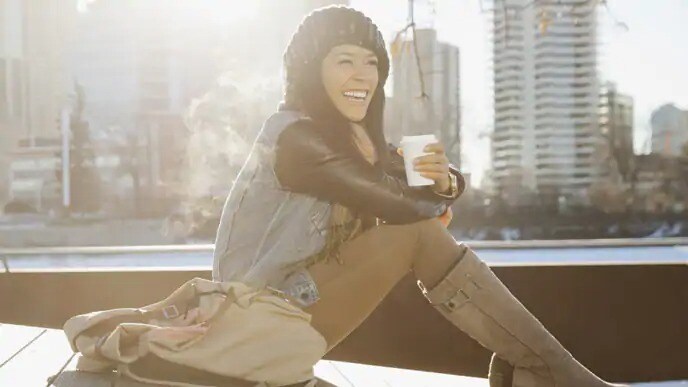 woman smiling outside drinking coffee