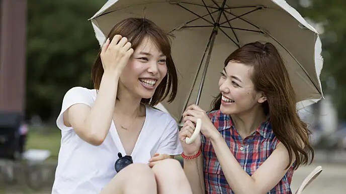 women laughing together under an umbrella