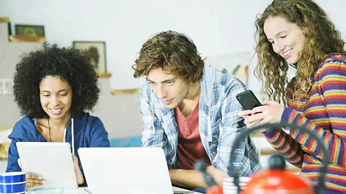 Group of people smiling while looking at laptops