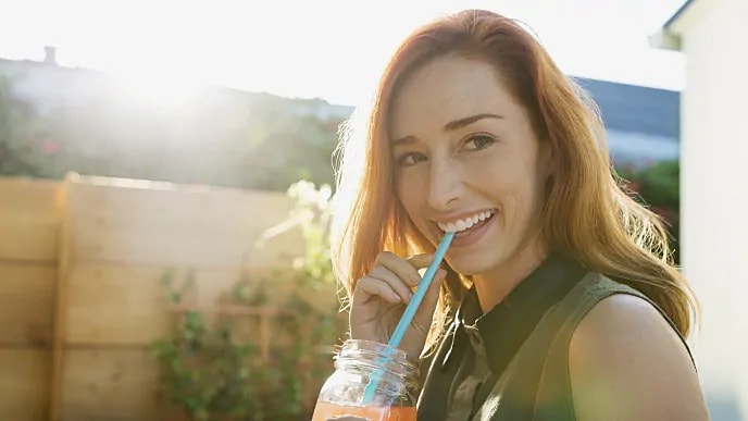 Woman smiling while sipping through a straw