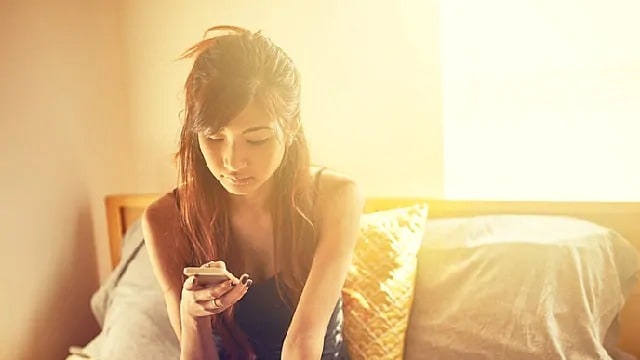 Woman looking down at cellphone in her hand