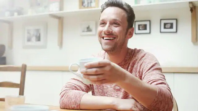 Man smiling while holding a mug