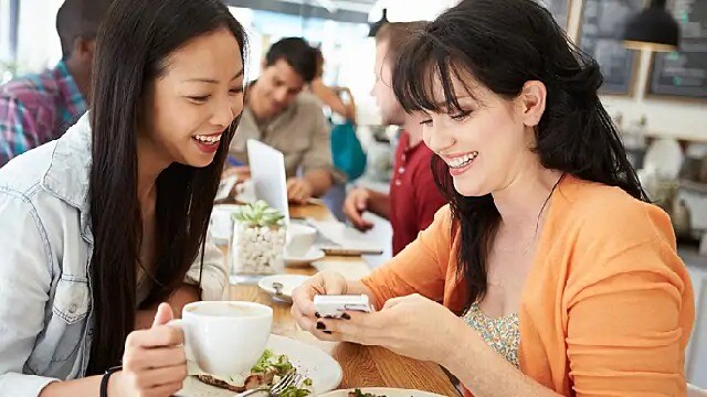 Two women smiling while looking at a cell phone