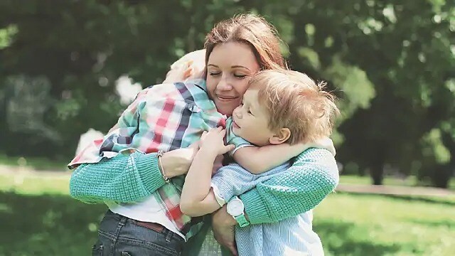 A woman smiles while holding two children