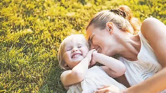 A woman and child smiling while lying on grass