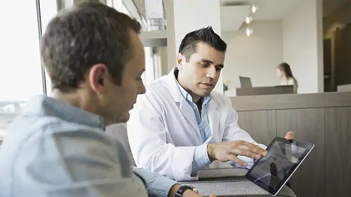 Dentist pointing out information on tablet to a patient