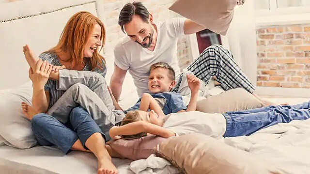 Family of four laughing while playing with pillows Family of four laughing while playing with pillows