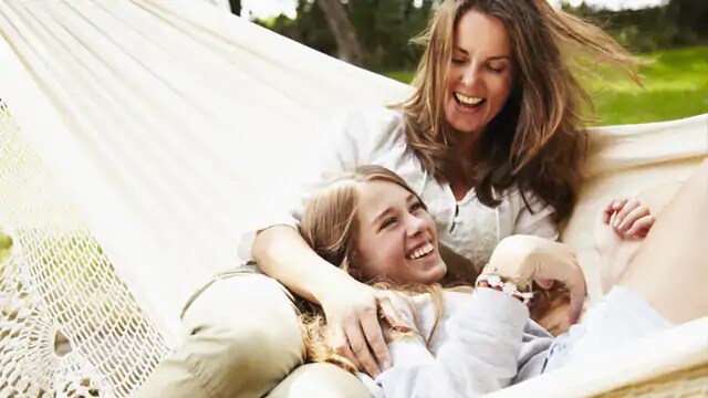 Two women smiling while lounging in a hammock
