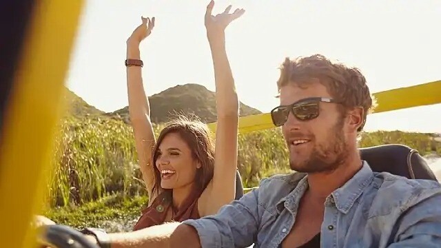 A man and a woman smiling while riding in a jeep