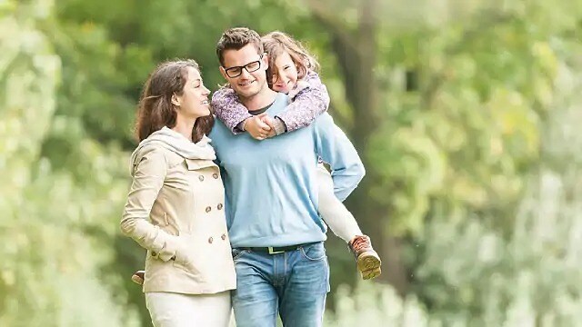 Man carrying child on his back while walking with a smiling woman