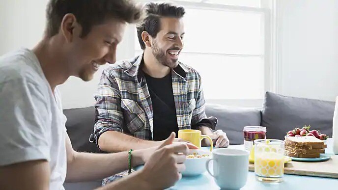 Two men smiling while sitting down for breakfast