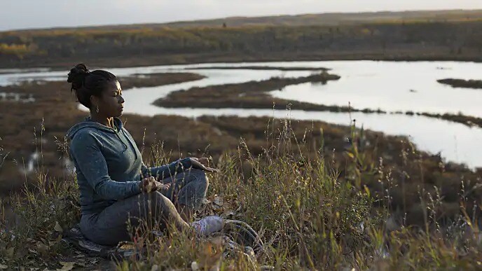 A woman meditating on the bank of a river