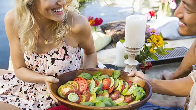 A smiling woman holding a bowl of salad