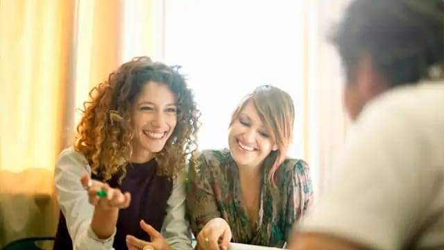 Two women smiling while sitting at a table