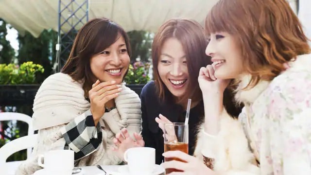 three asian girls are having coffee in an outdoor cafe