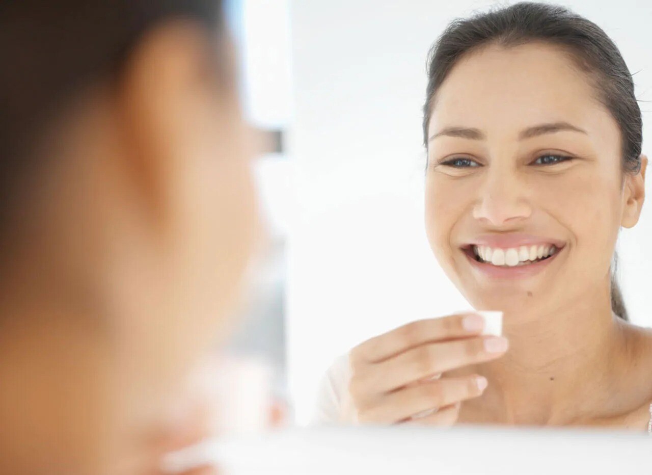 Woman with white teeth smiling into a mirror