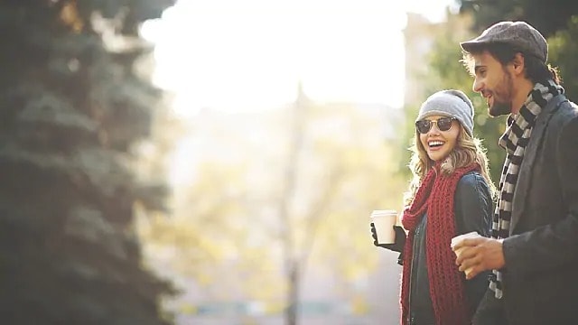 A couple is taking a walk in the park with coffee