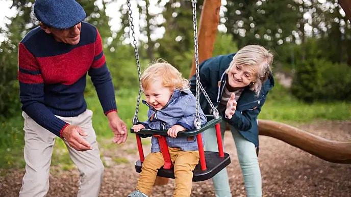 Grandparents pushing a child in a swing