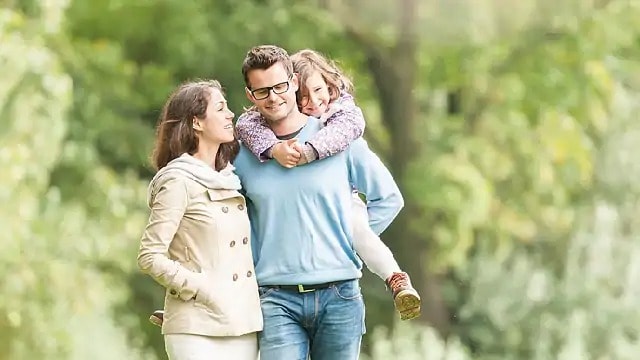 Man carrying child on his back while walking with a woman
