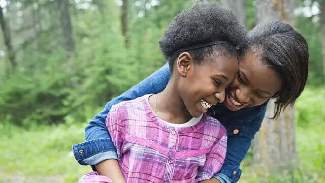 A smiling woman hugging a smiling child