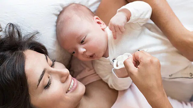 Woman lying on her back while holding an infant