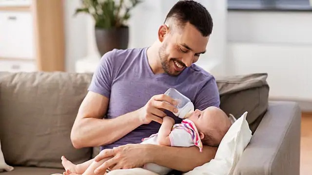 Man giving an infant a clean bottle during a feeding