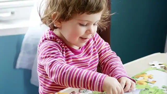 Smiling child putting together a puzzle