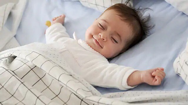 smiling infant sleeping on a bed