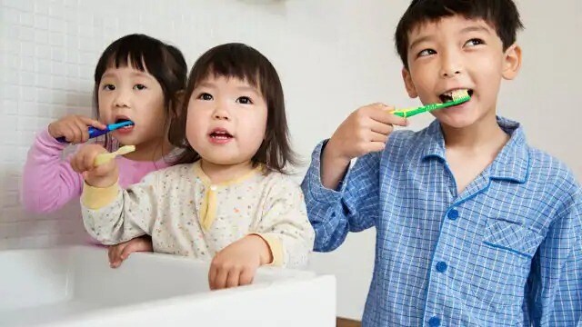 Three children brushing their teeth