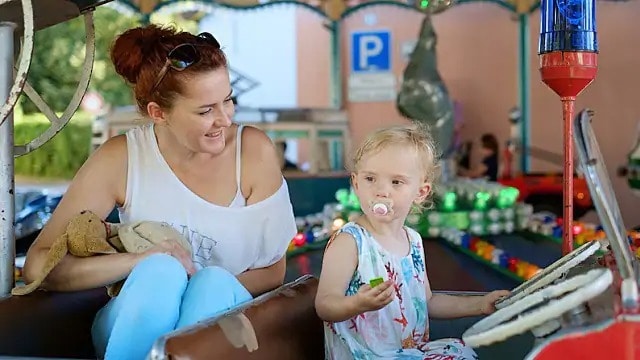 Woman smiling at a young girl with a pacifier.